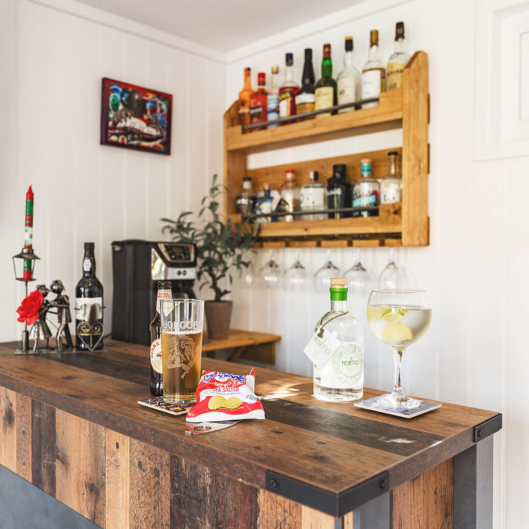 timber garden bar topped with lots of bottles of alcohol