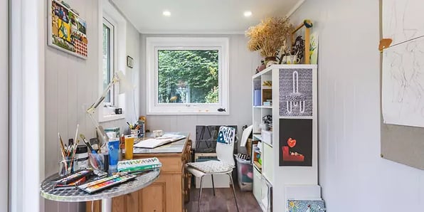 Interior of a garden room artists studio with paints & brushes on desk