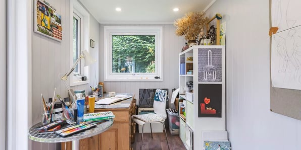 Interior of a garden room artists studio with paints & brushes on desk