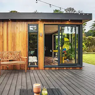 A timber deck with a large garden man cave and a bench and table on it