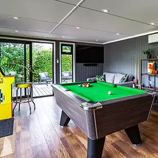 a garden man cave room with a pool table and large flat screen television in it