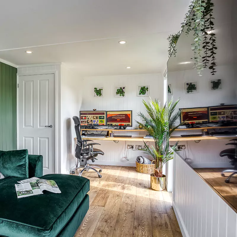 Large summerhouse office pod interior with green velvet sofa