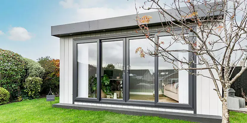 Zero maintenance garden office with black sliding doors open so you can see desk 