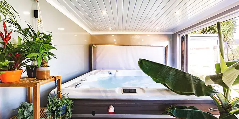 garden room with hot tub and green tropical plants 