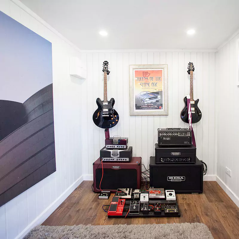 electric guitars nanging on wall, amps on floor underneath
