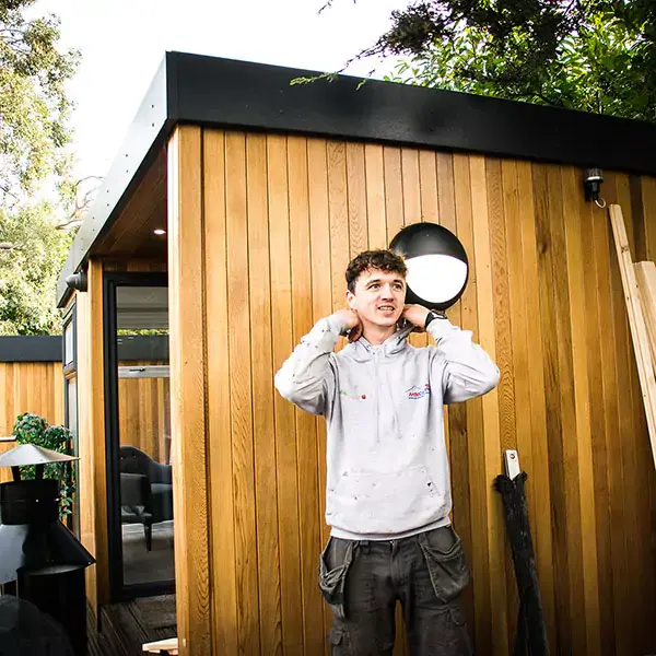 man in branded arctic cabins cabin master grey hoodie in front of cedar garden office at Nottingham Show Site