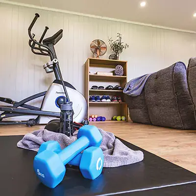 Inside a garden gym room with exercise bike, mats and weights