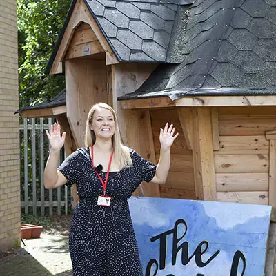 Teacher excited to be outside her new unique, quirky school hut