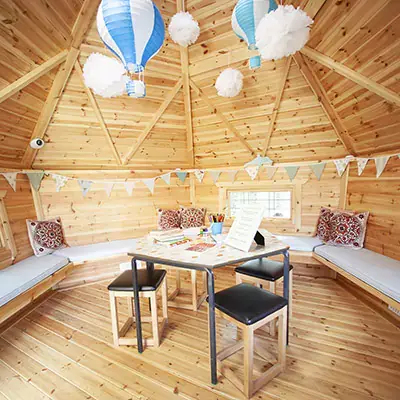 Interior of a timber school cabin with hanging decorations an seating