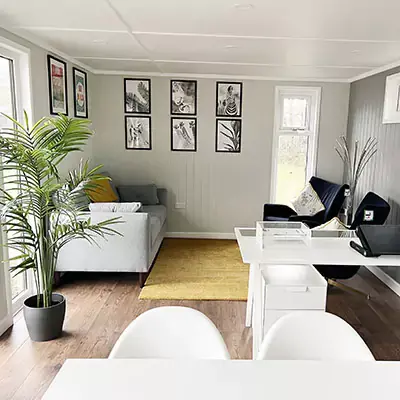 Interior of a bespoke school room cabin with plants, desks and pictures on wall