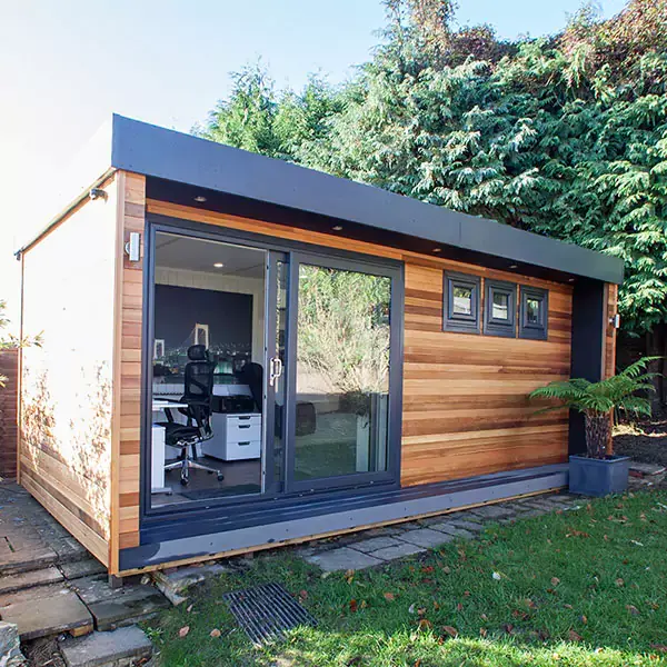 External view of Cabin Master Garden Music Room with view into desk chair and studio equipment and large green lawn area