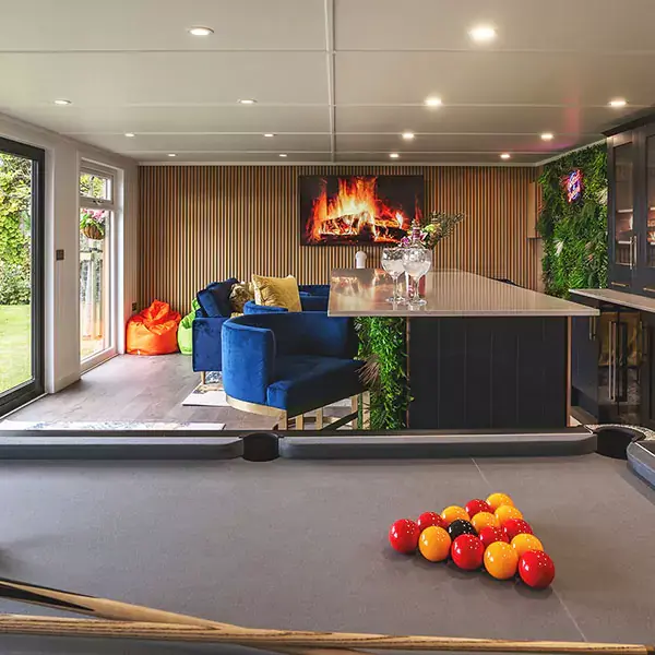 Interior of a garden room bar with bright decor, plant wall and neon sign