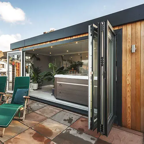 Large cedar outdoor building for hot tub with open bifold doors and sunloungers outside