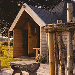 Timber camping cabin for glamping with BBQ and planters outside