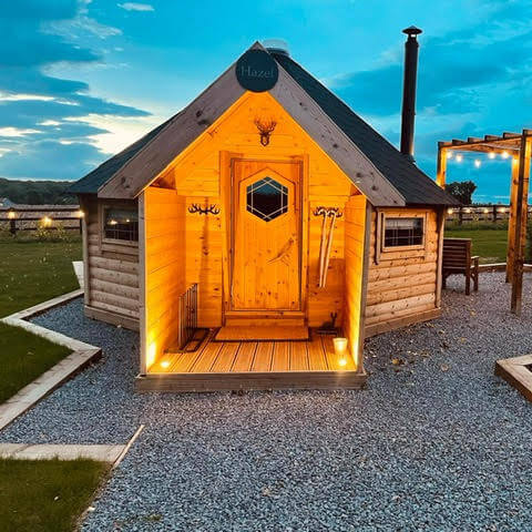 Exterior of a timber camping cabin hut at dusk
