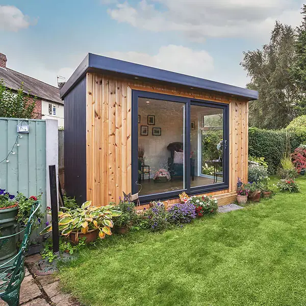 Outside a redwood timber garden room with english flowers in garden